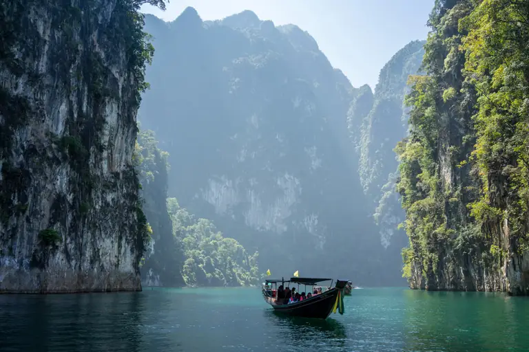 A boat resting between towering limestone cliffs near Railay, Krabi
